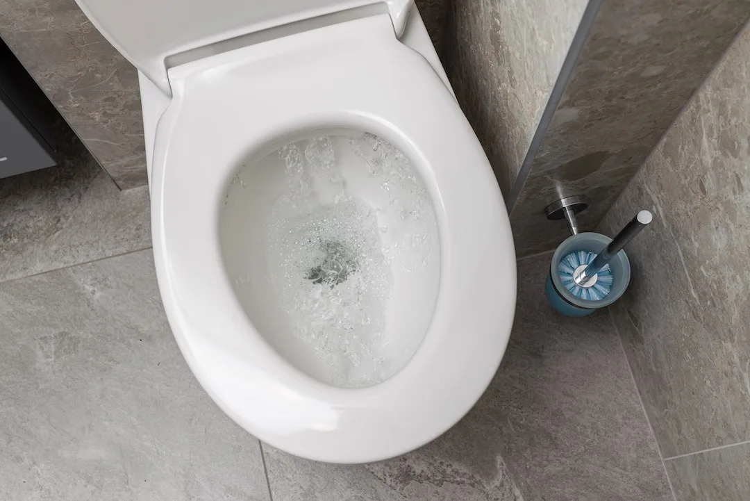 Water is running in the toilet in the bathroom, view from above.